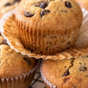 Banana Chocolate chip muffins stacked with top wrapper peeled off to show texture.
