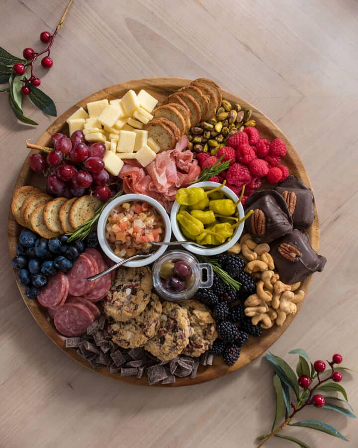 A charcuterie board with cured meats, cheese, and snacks on a wood background.