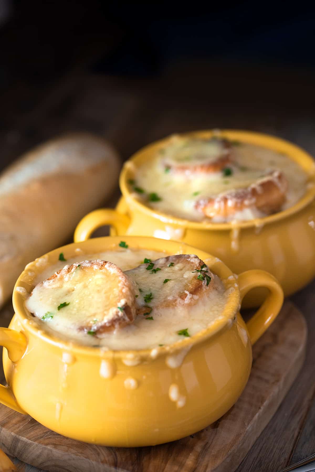 Two bowls of French onion soup with croutons and melted Swiss cheese on top.