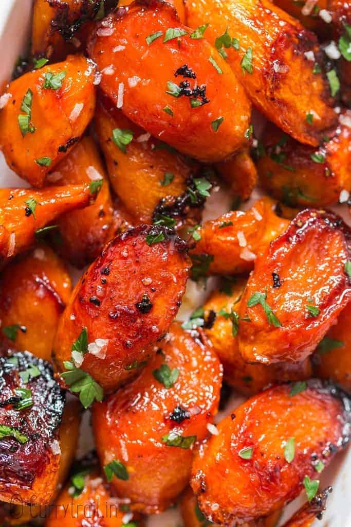 Garlic honey carrots closeup in a pan with parsley sprinkled on top as garnish.