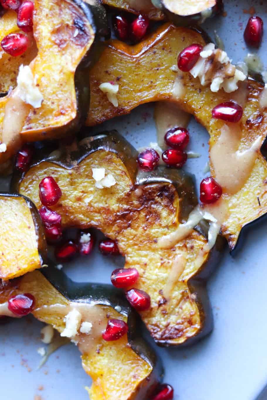 Sliced and roasted maple acorn squash with pomegranate seeds sprinkled on top.