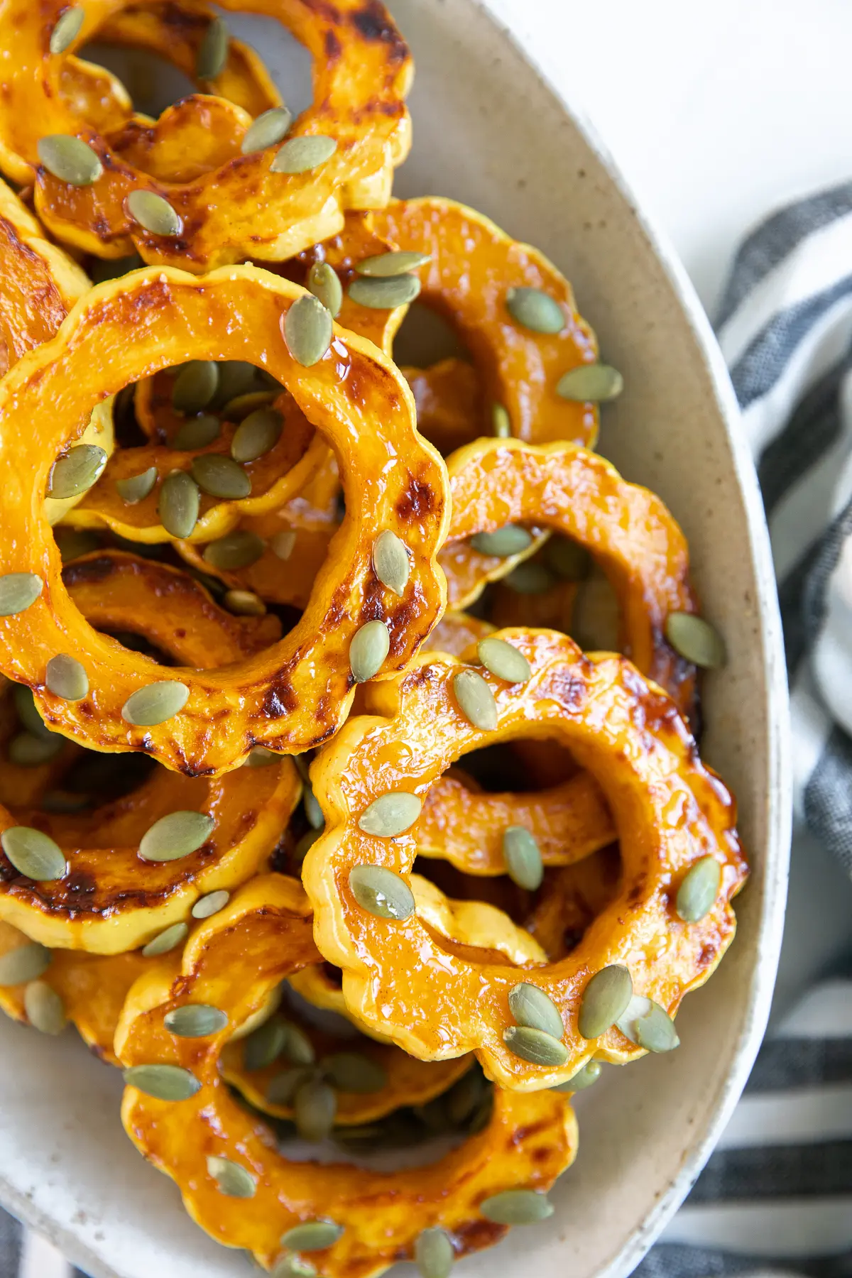 Roasted delicata squash rings with seeds on top in a bowl.