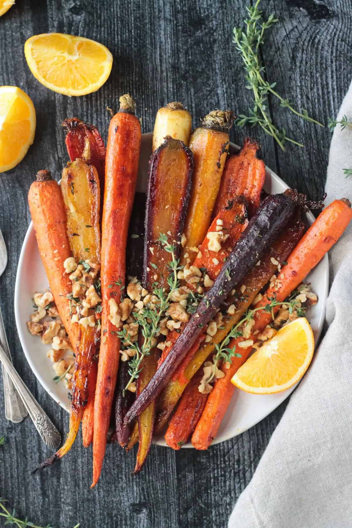 Roasted whole rainbow carrots with walnuts and thyme on top.