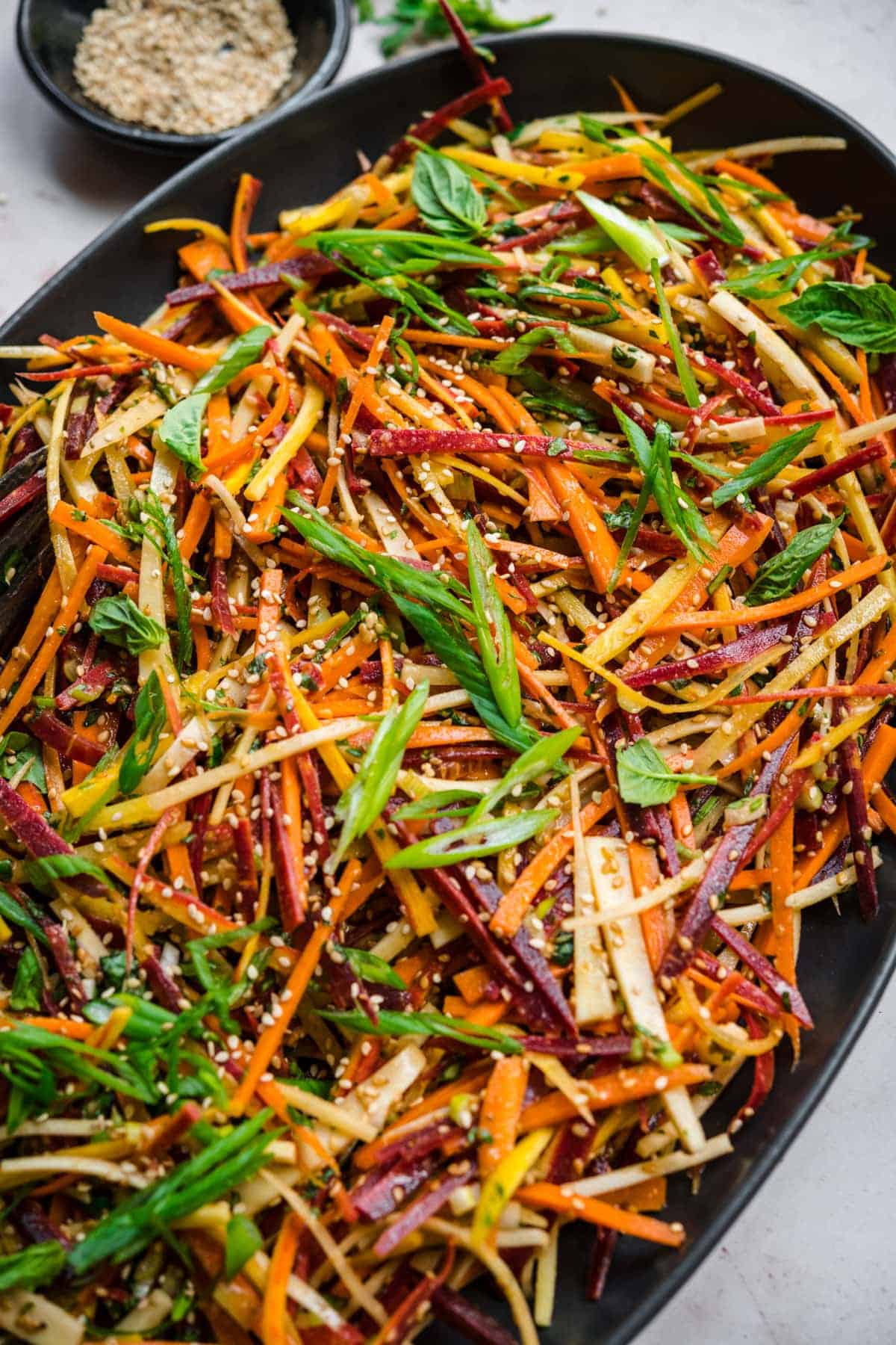 Shaved carrot salad on a black plate.