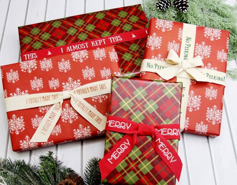 Four Christmas gifts wrapped in plaid and snowflake prints tied with custom ribbon .