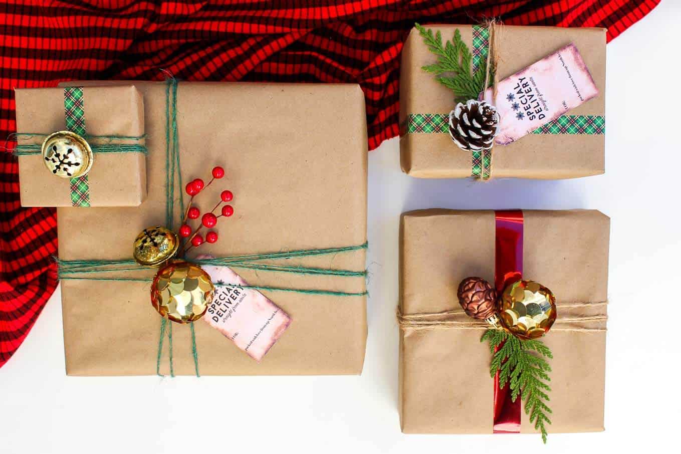 Brown craft paper wrapped Christmas gifts with yarn, ribbon and string and ornament, berry and pinecone toppers.