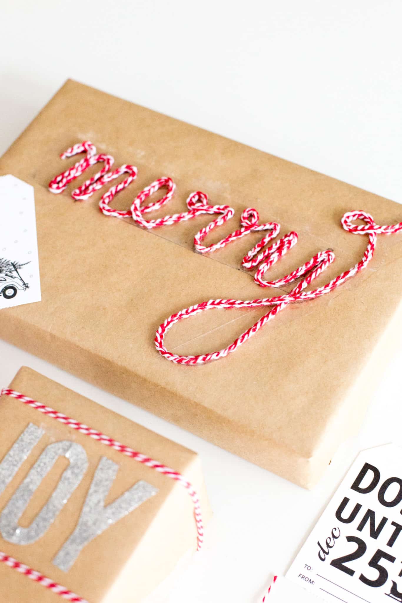 Brown paper package with red and white twine star decor and white gift tag with car.