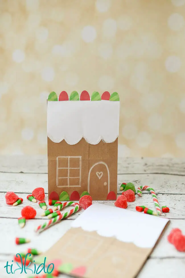 Gingerbread House Brown Paper Bag Package with gum drops and candy canes in the background.