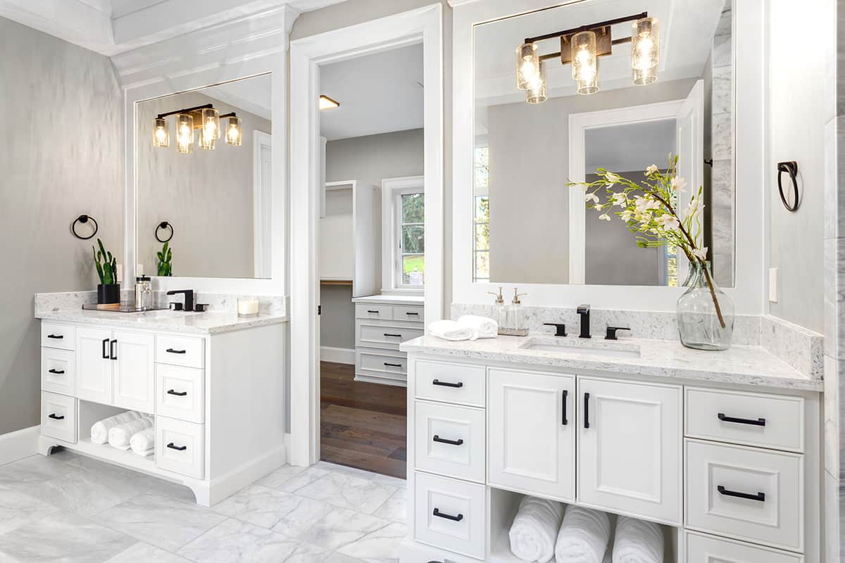 Transitional white bathroom with white tile floors and two separate sink stations.