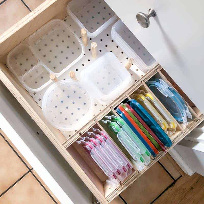 Kitchen drawer with diy pegboard storage to organize Tupperware containers and lids.