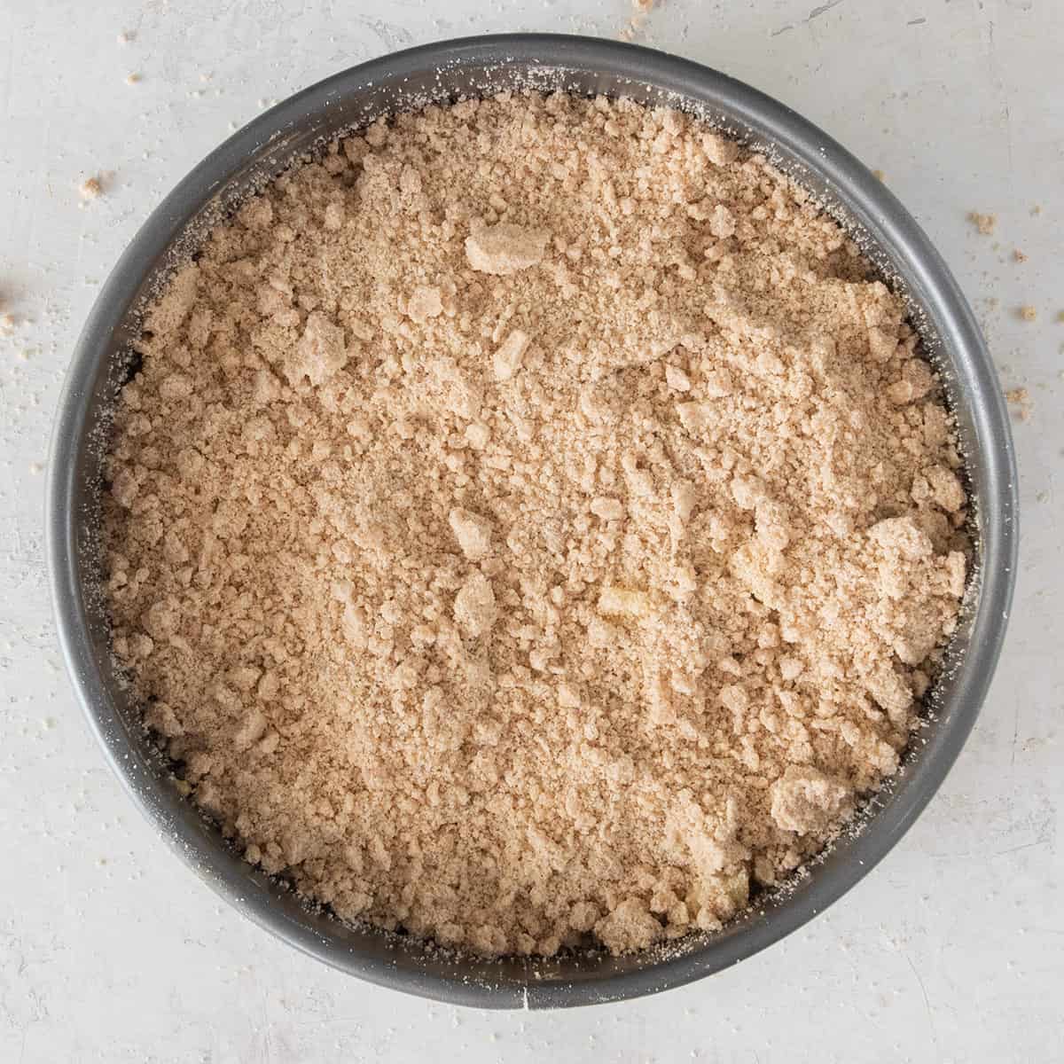 Overhead of an apple crumb pie before going into the oven showing the crumbly texture of the streusel topping.