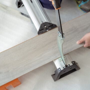 Man cutting vinyl plank flooring for installation.