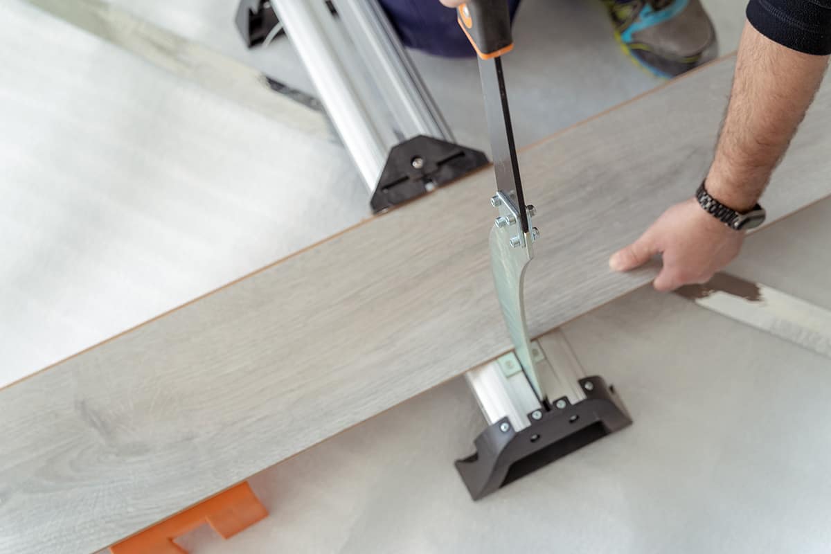 Man cutting vinyl plank flooring for installation.