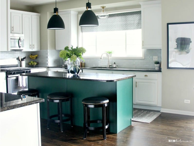 Modern kitchen with white cabinets and black countertops. Black and green island accent.