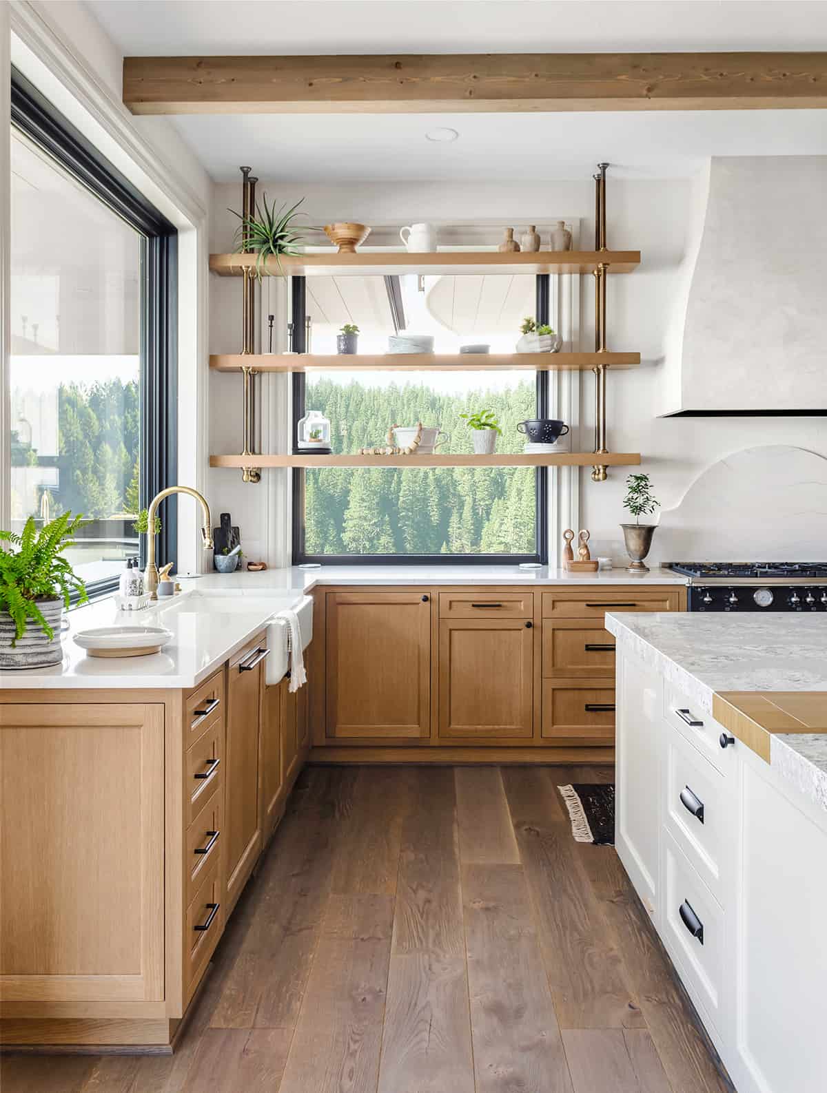 Natural light wood kitchen with large windows, exposed beams, and copper pipe shelving.