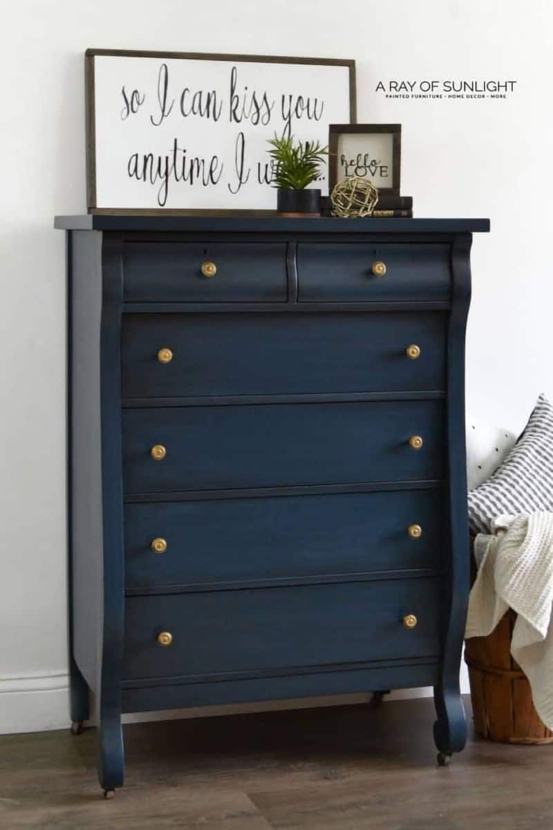 Navy dresser with gold knobs and black and white signs as accent decor.
