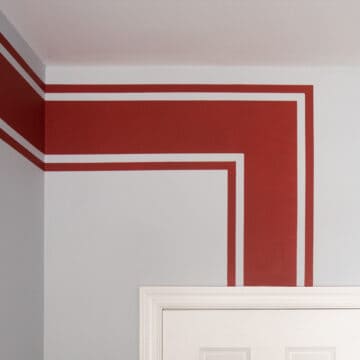 Single horizontal stripe in red racing stripe motif painted on a wall.