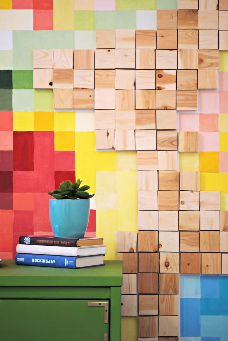 Pixelated wall mural with bright painted squares in primary and pastel colors with wooden squares anchoring design.