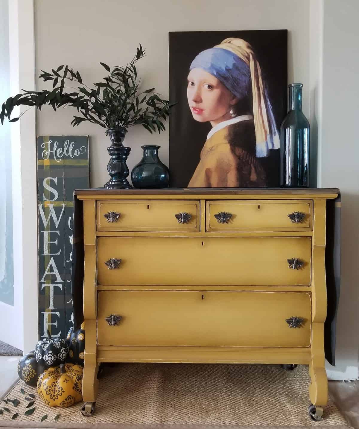 Goldenrod yellow painted sideboard table with three drawers.