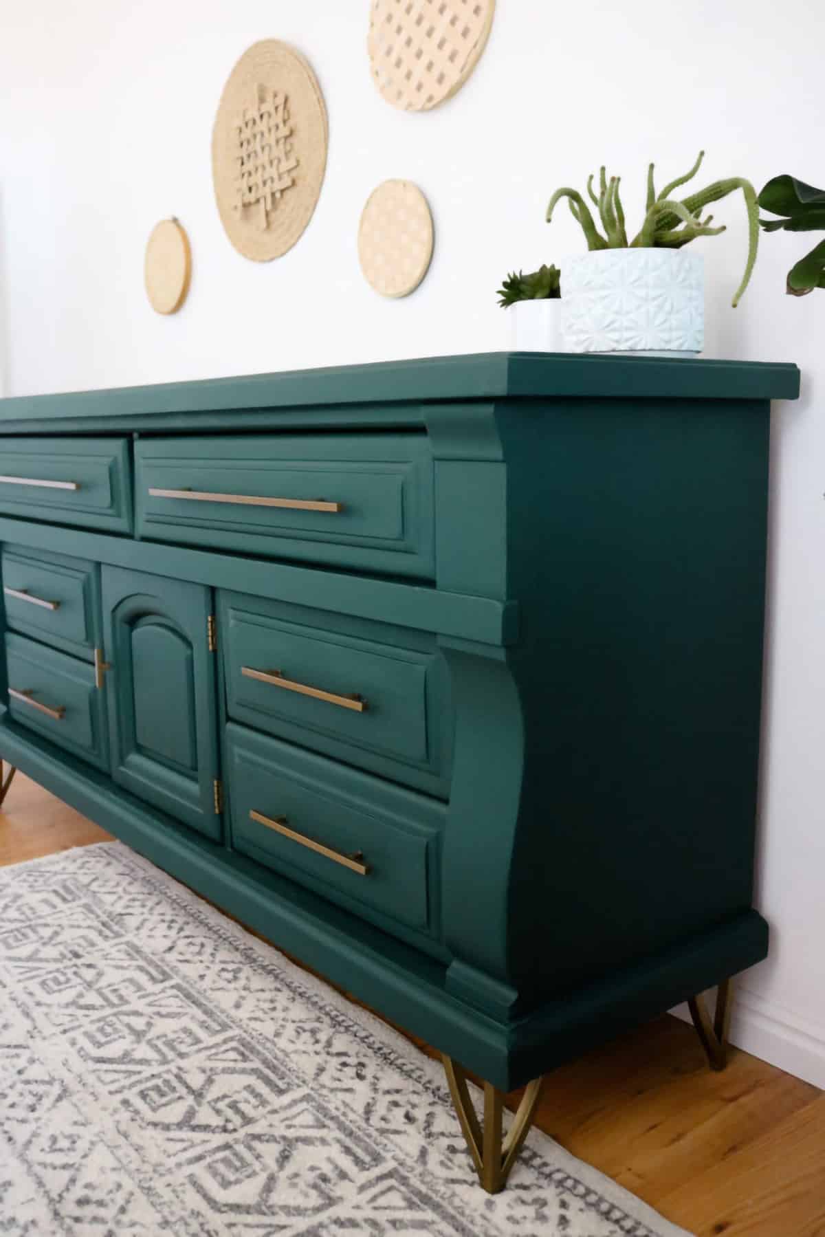 Hunter green dresser with brass hardware on gray and white patterned rug in bohemian style.