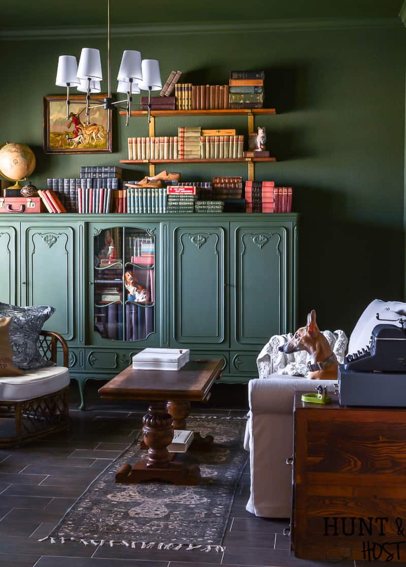 Dark green living room with built in green bookcase in front of couch.
