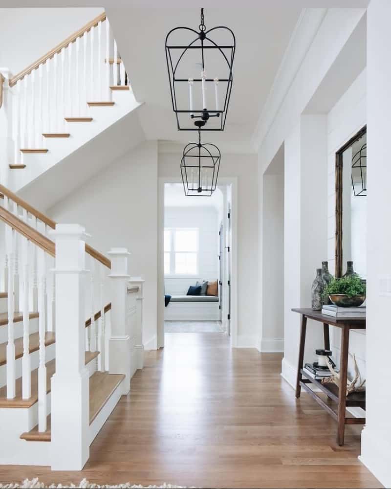 Narrow hallway with entryway lighting idea using cage chandeliers to illuminate the space.