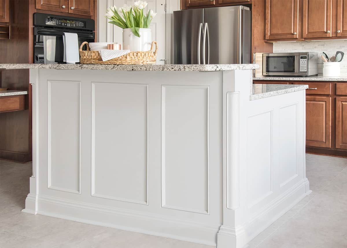 Large grey kitchen island with breakfast bar in traditional trim and two tone different color from the cabinets.