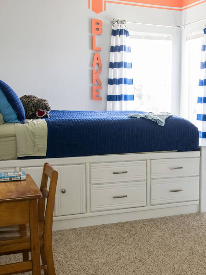 Boys bedroom in grey and navy with red accents and a red racing stripe painted on the wall.