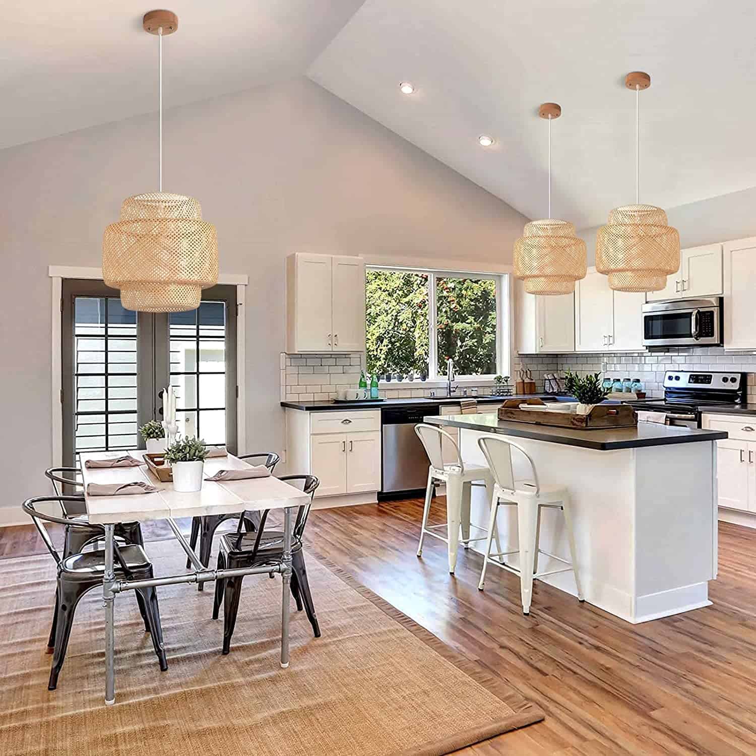 Three neutral basket weave style pendant lights placed above kitchen island and dining area in black and white modern kitchen featuring natural elements.