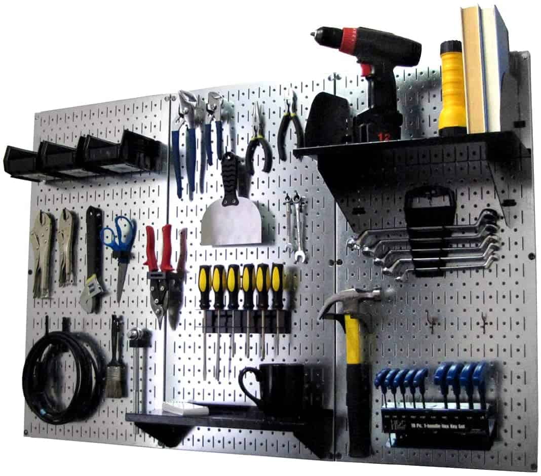 Metal pegboard organizer for the garage with small hand tools, hooks, and bins on it.