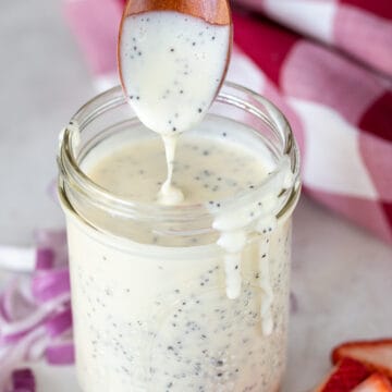 Homemade poppy seed salad dressing recipe pouring from a spoon into a mason jar to show thickness.