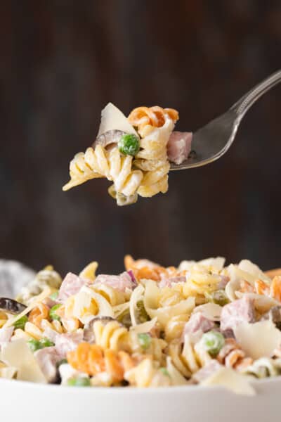 Ham Pasta salad with Ranch dressing and peas piled on a fork.