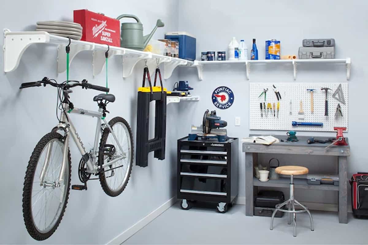 An organized white garage with shelves hanging around the room to hold cleaning supplies and other tools.