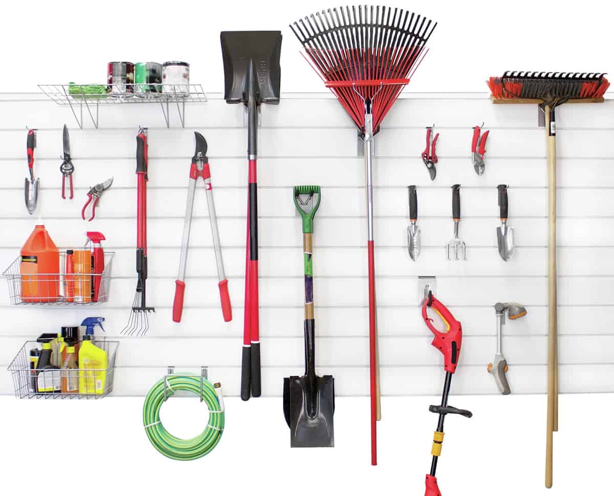 Slat panel organizer hanging on a wall with yard tools and gardening supplies on it.