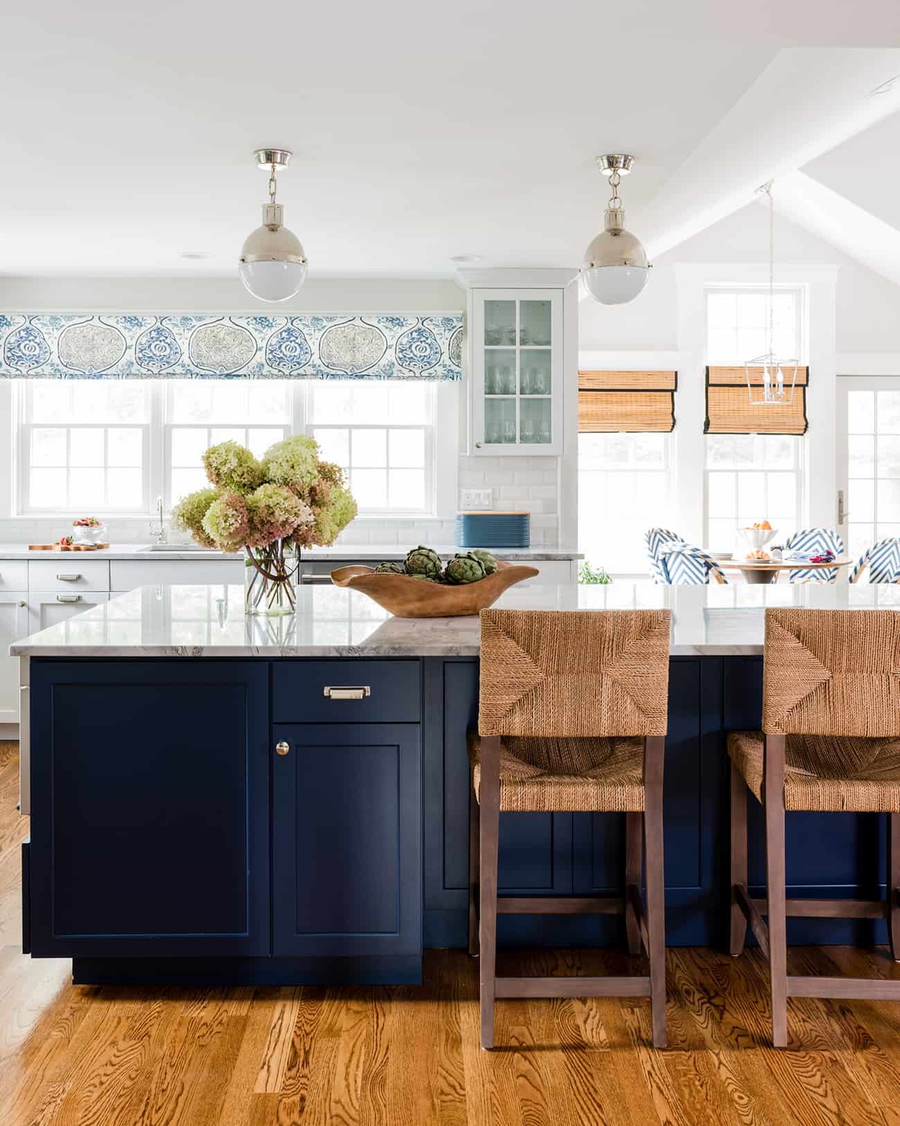 Coastal chic kitchen with large center island painted in Sherwin Williams Naval with white marble countertop. 