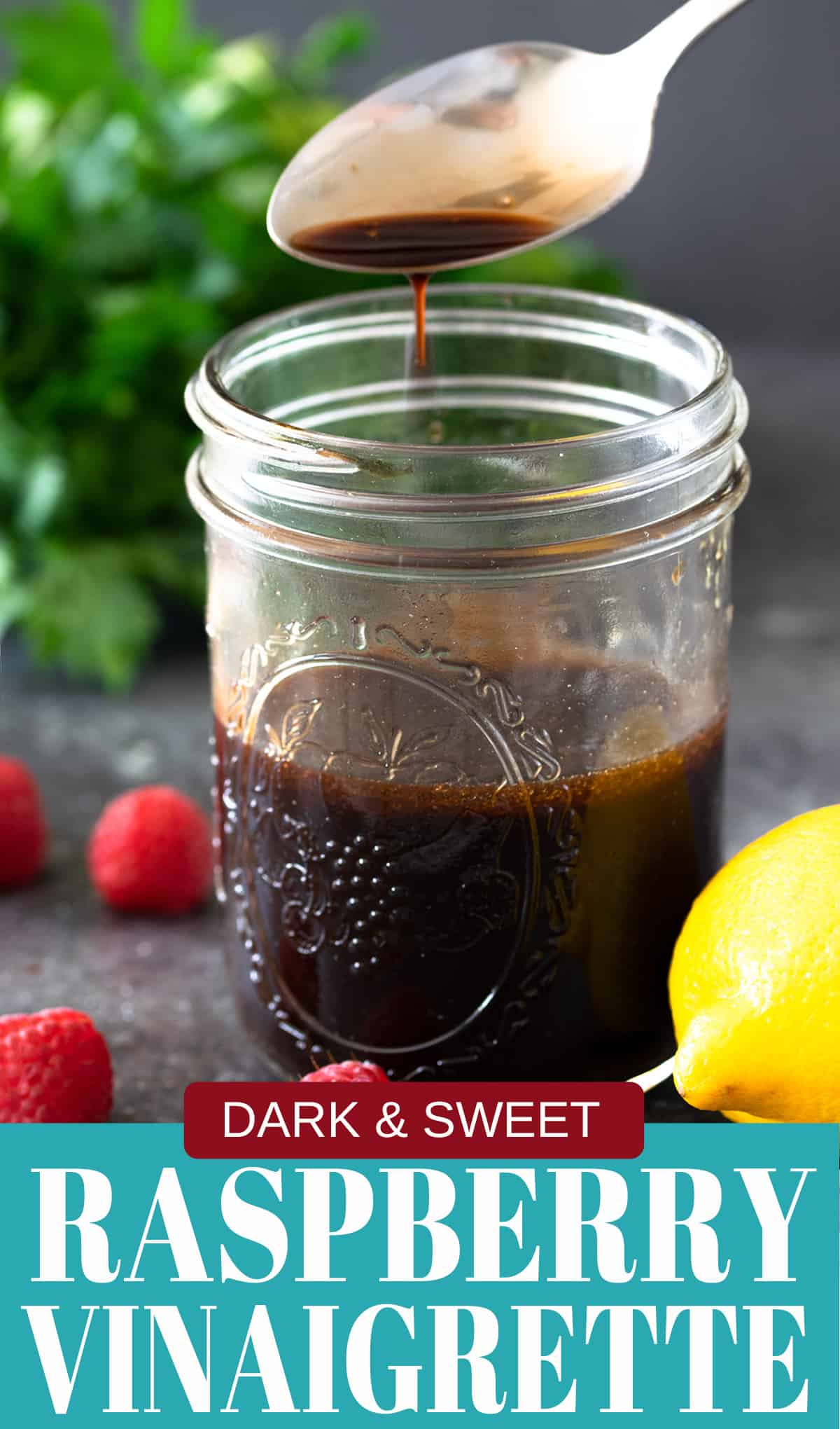 Raspberry Vinaigrette dressing in a jar with a spoon above containing dressing dripping.