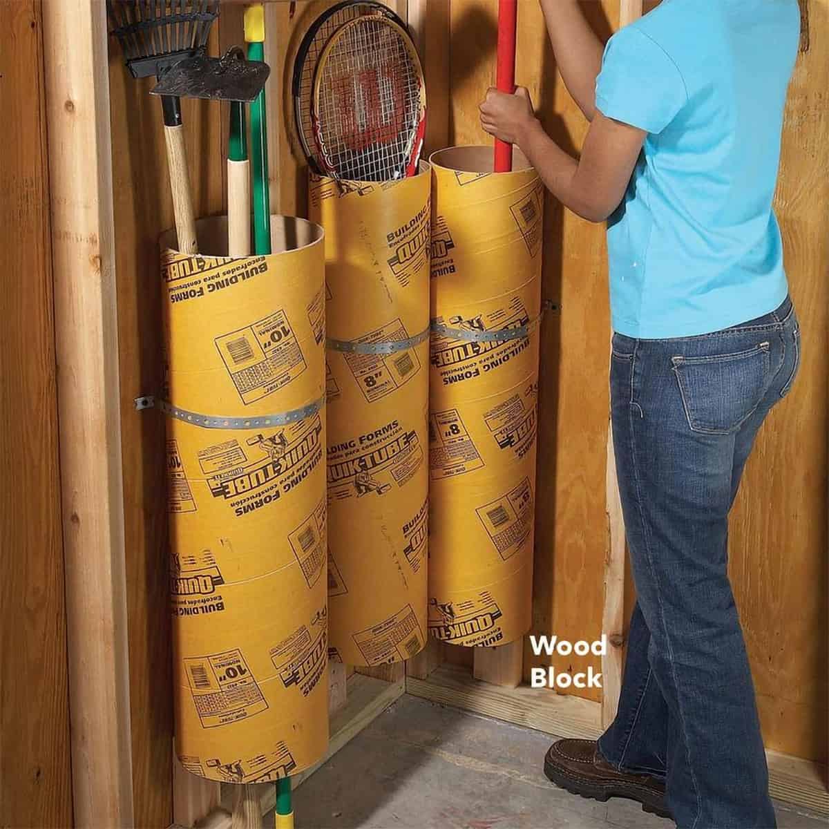 Three cement tubes attached to the wall. to hold yard tools for an organized garage space.