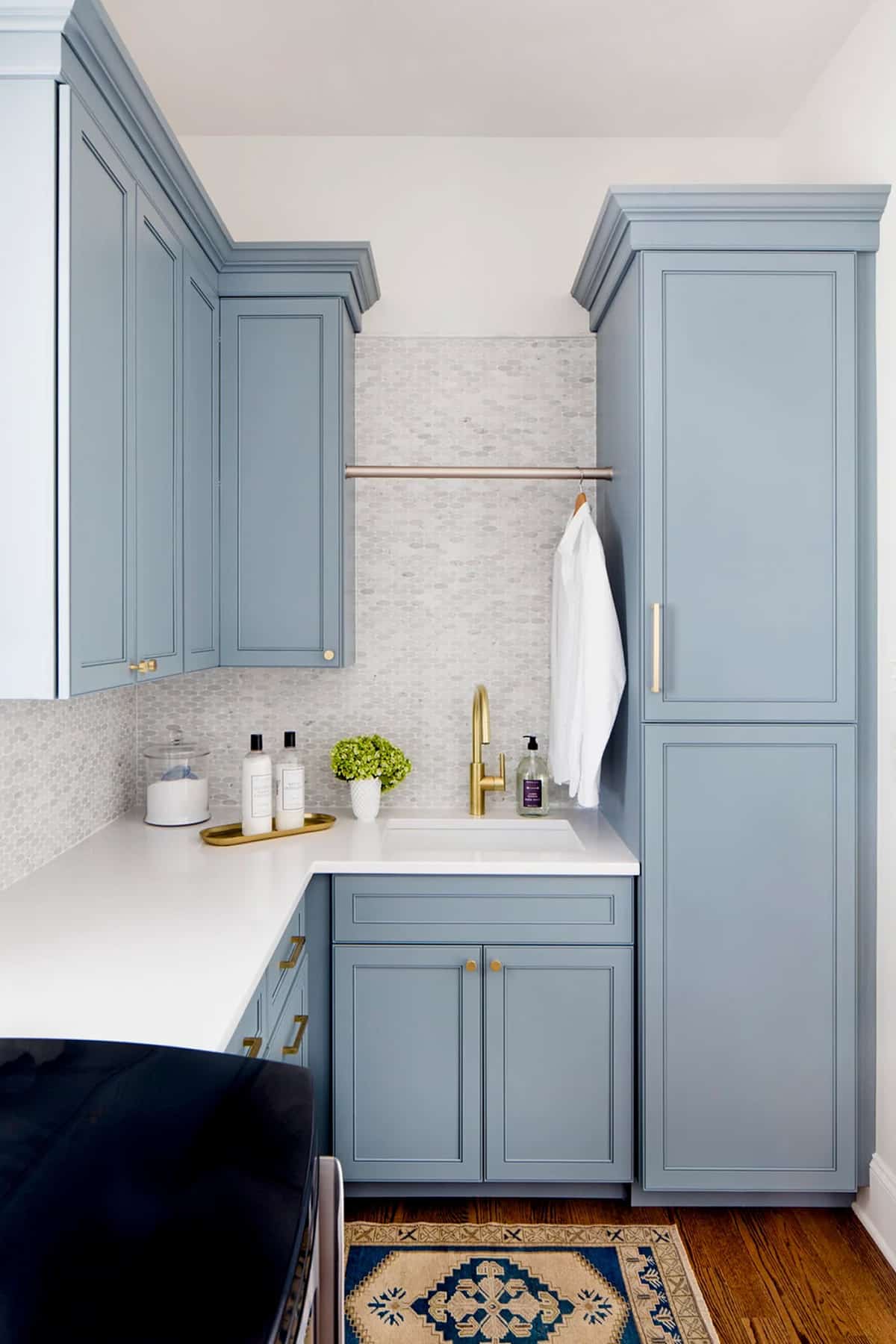 Modern laundry room Benjamin Moore Van Courtland Blue cabinets. Brass hardware and white countertops and backsplash.