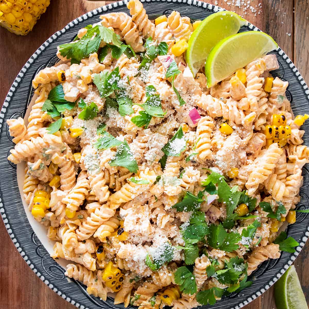 Flatlay of mexican corn salad with cilantro on top and two lime wedges.