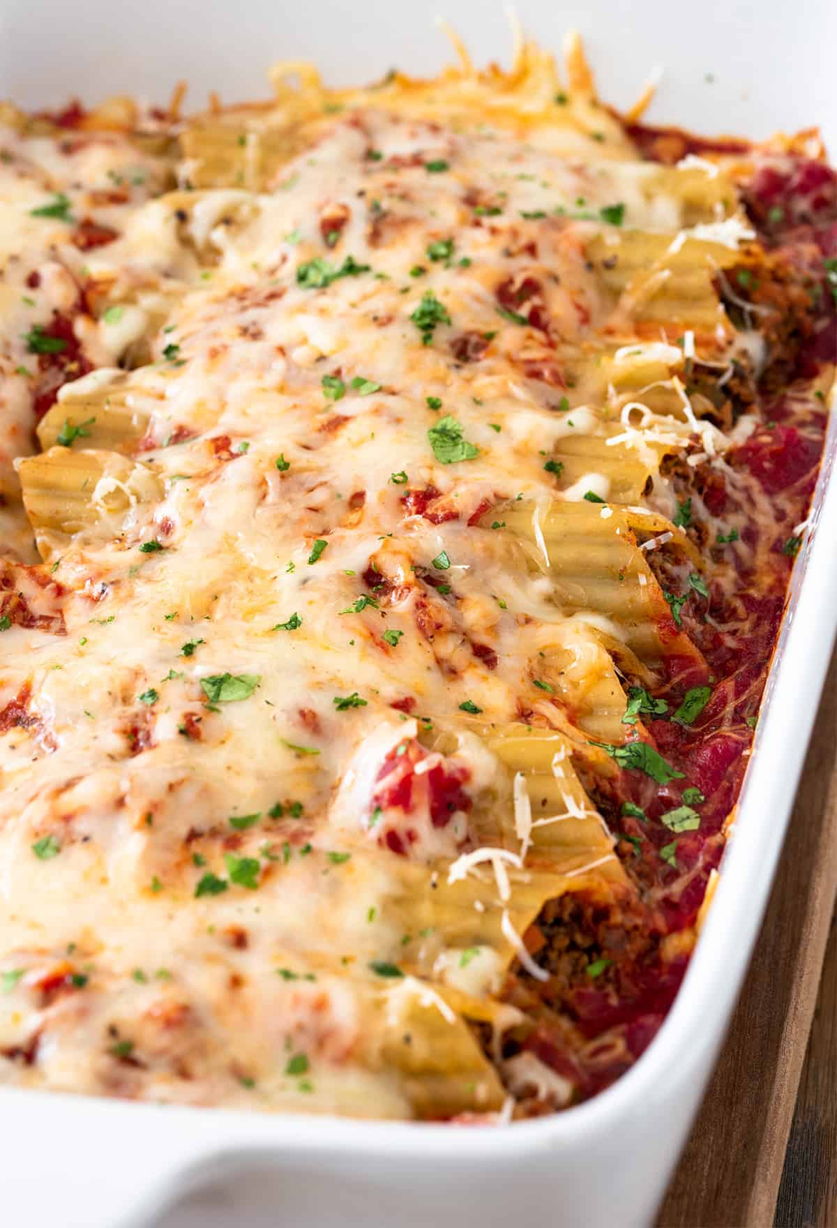 Side view shot of beef cannelloni pasta in a casserole dish.