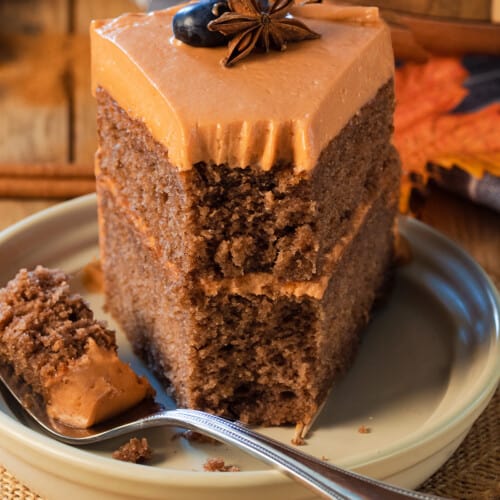 Closeup of a fall layer cake with orange frosting and a fork in front of the cake.