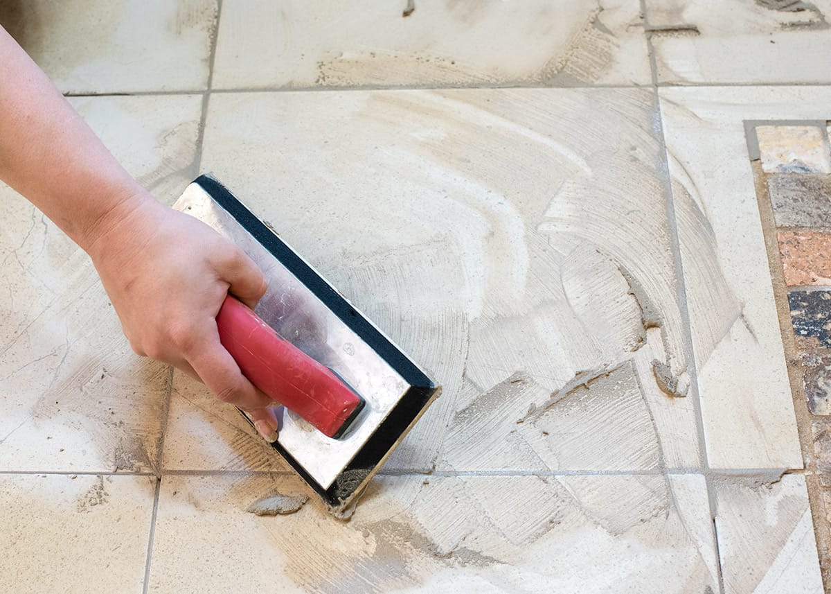 Using a rubber float for grouting tile in kitchen.