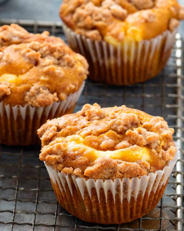 Pumpkin muffins with crumb topping on a cooling rack.