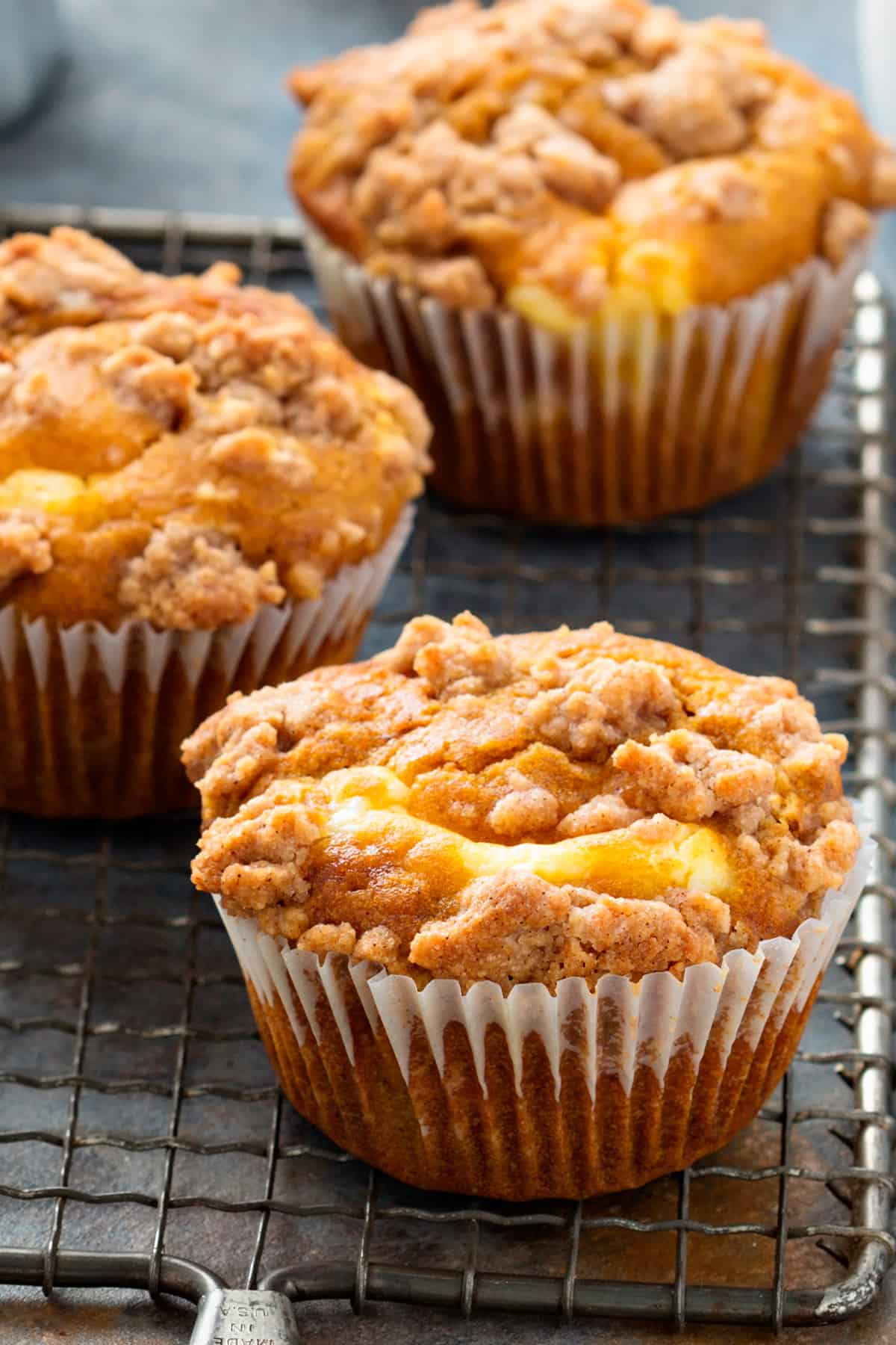 Pumpkin muffins with crumb topping on a cooling rack.