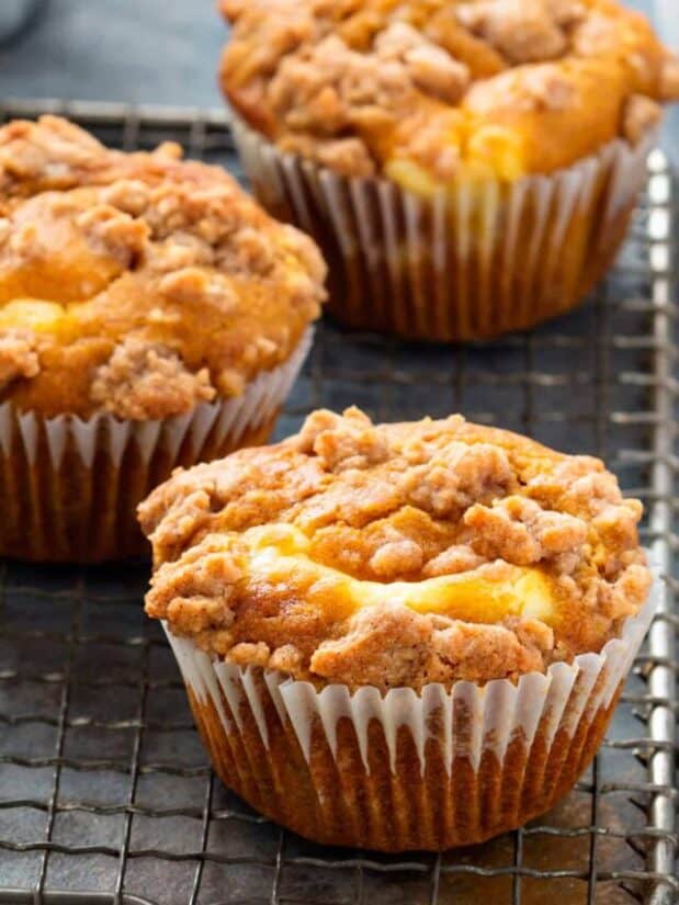 Pumpkin muffins with crumb topping on a cooling rack.