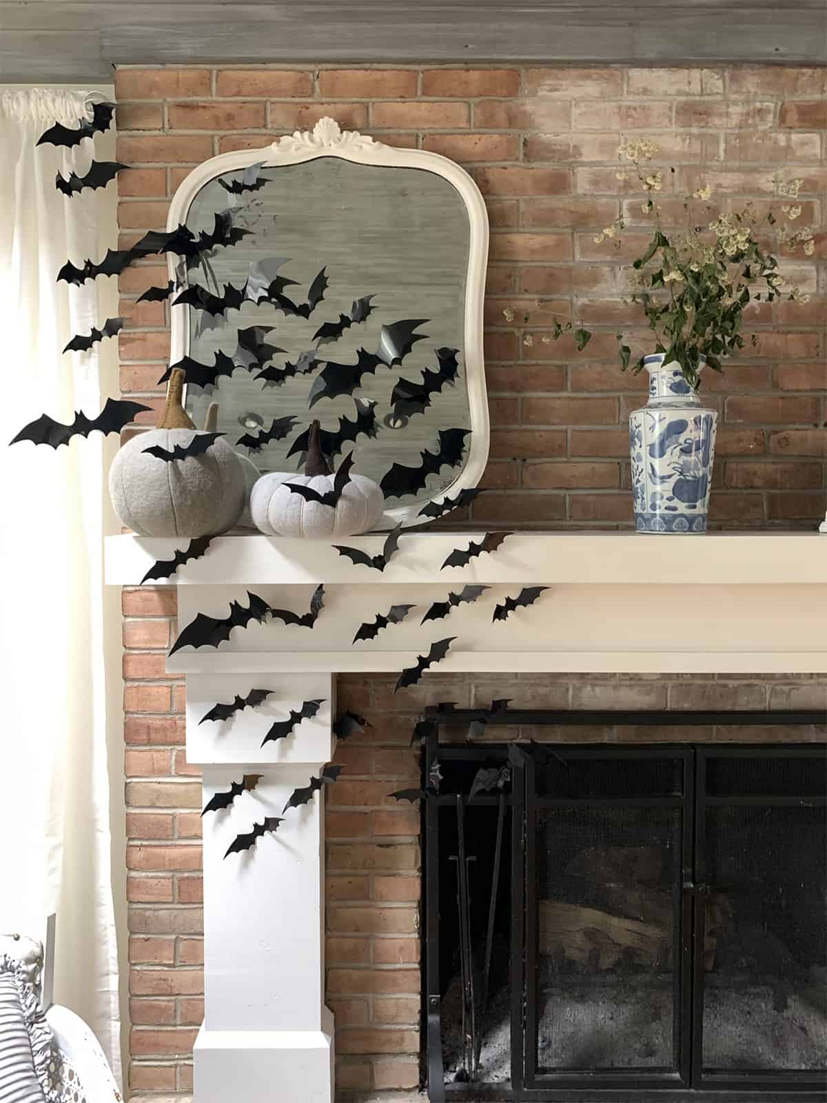 Creepy mantel with swarming bats from fireplace opening towards white antique mirror.