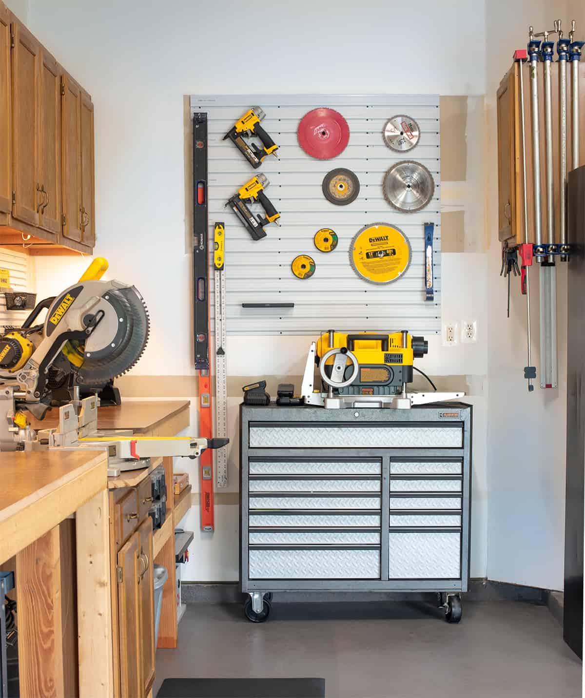 Organized garage with workbench, tool chest, and slatwall pegboard above tool chest.