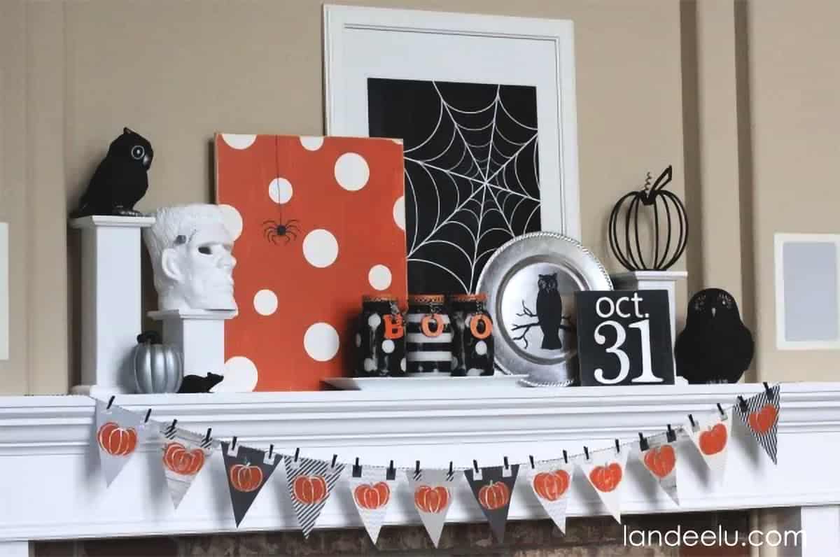 Modern black, white, and orange Halloween mantel with pumpkin garland, polka dot palette art, and framed spider web print.