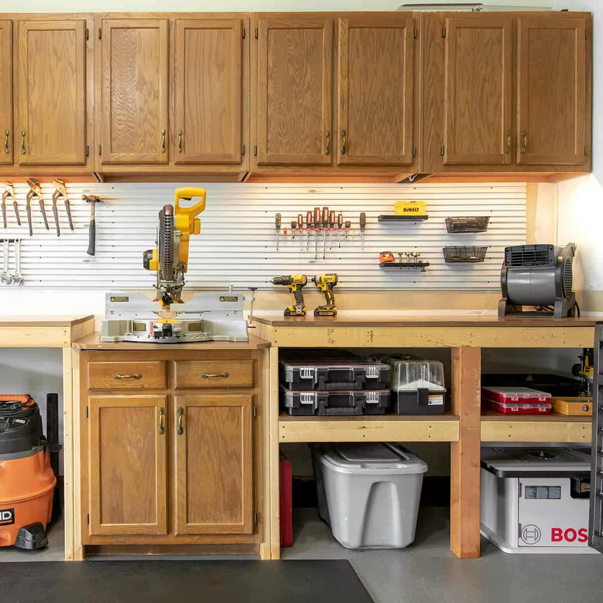 Garage woodworking miter saw station with cabinets and tool storage.