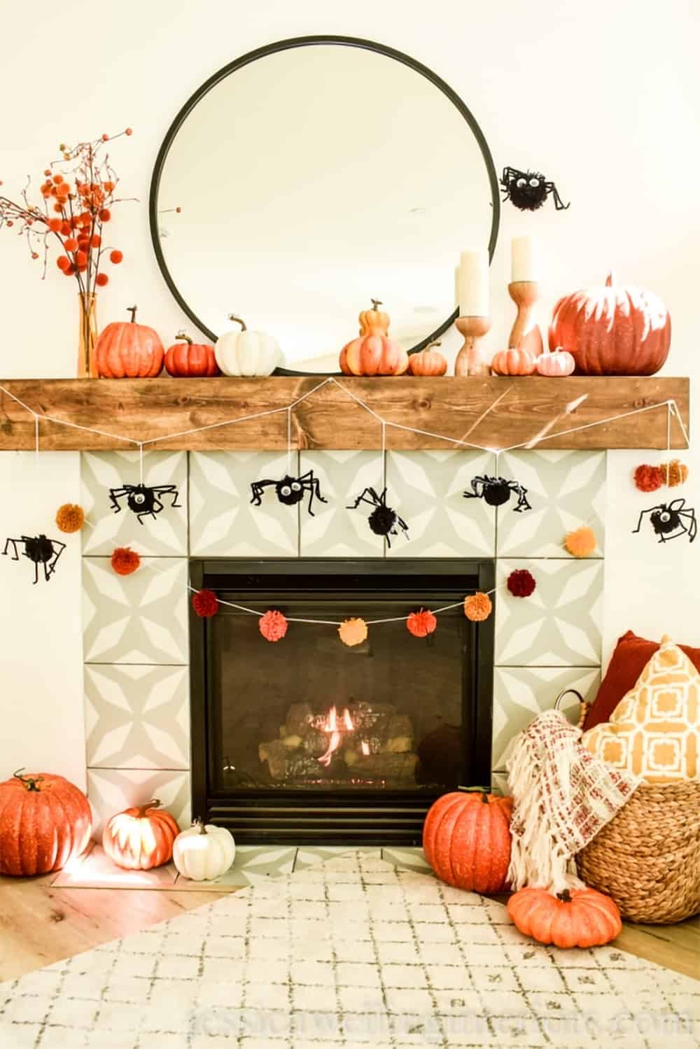 Cozy fall white mantel display with orange pumpkins and gourds, and DIY spider pompom garland.